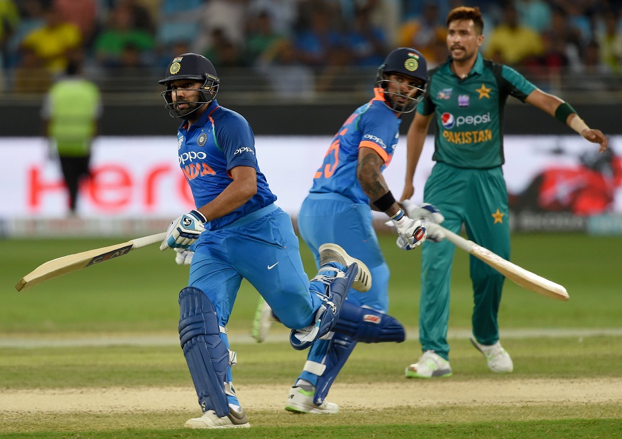 Indian cricket team captain Rohit Sharma (L) and Shikhar Dhawan runs between the wickets as  Pakistan cricketer Mohammad Amir (R) looks on. PHOTO: AFP